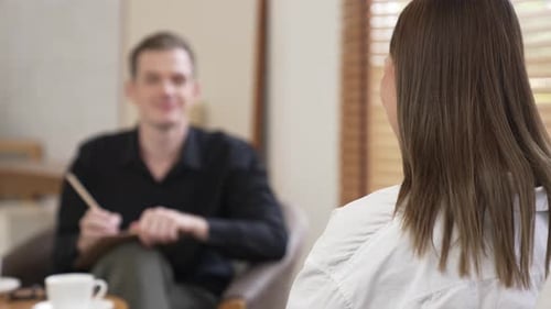 Woman Talking to Man with Clipboard in Office