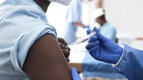 Professional Doctor Injecting Coronavirus Vaccine To Male Patient In The Hospital. medium shot