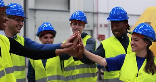 Multiracial engineers stacking hands in robotic factory demonstrating teamwork