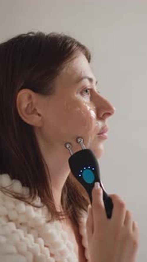 Woman Using Facial Roller in Home Setting