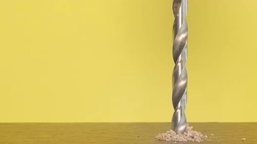Closeup of a Woodworking Drill Rotating on a Yellow Background