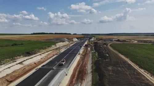 Der Lkw fährt unter einem Metallrahmen auf einer unvollständigen Autobahn