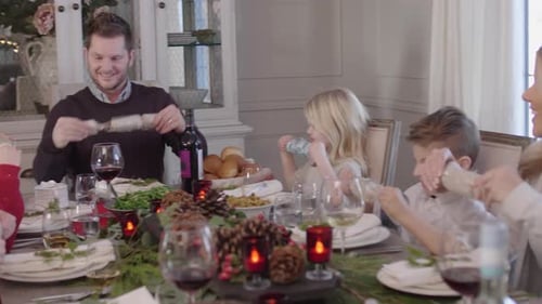 Family Pulling Christmas Crackers at Festive Dining Table