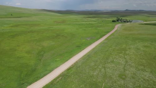 Aerial View of Dirt Road in the Middle of Vast Green Valley