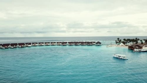Vídeo de drone de um resort tropical nas Maldivas, recife de lagoa azul, clima ensolarado, turquesa rasa