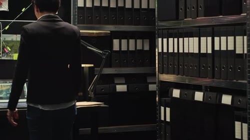 Woman in Dark Office with Shelves of Binders
