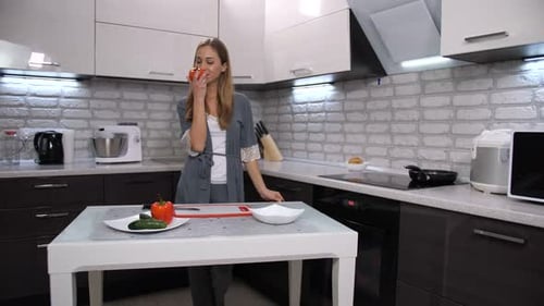 Woman Holds Tomato in Modern Kitchen
