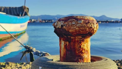 Rusty Bollard Tied Wooden Fishing Boat With Rope In Harbor