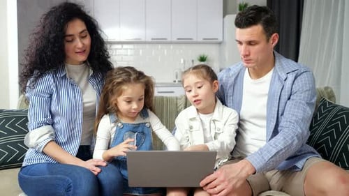 Des parents attentifs regardent des frères et sœurs excités jouer sur un ordinateur portable