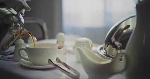 Gloved Hand Pouring Tea For Luxury Hotel Room Service