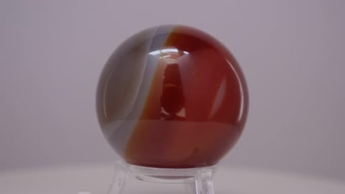Esfera mineral de cristal de ágata que gira sobre una mesa giratoria frente a un fondo blanco