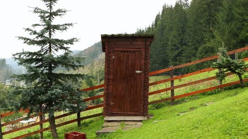 Rustic Wooden Outhouse in Green Countryside Setting