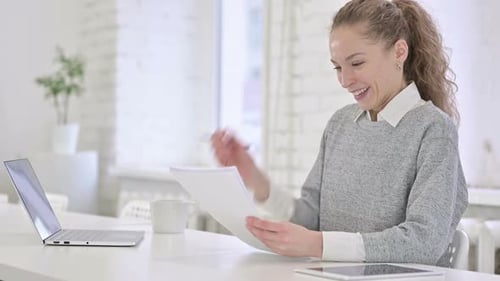 Woman Reading Documents at Desk in Bright Office