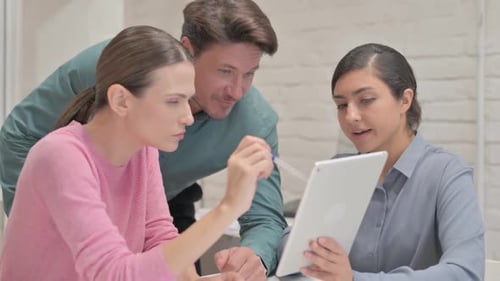 Creative Team Discussing Online Information on Tablet in Office