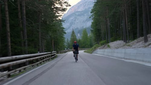 Cyclist cycling up hill, pedaling hard to get on a green mountain in the beautiful Dolomites Italy E
