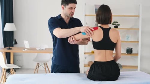 Therapist Applies Therapeutic Tape to Woman's Shoulder