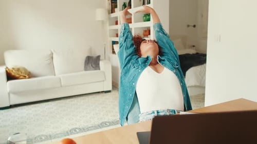 Woman Stretching Back at Desk in Apartment