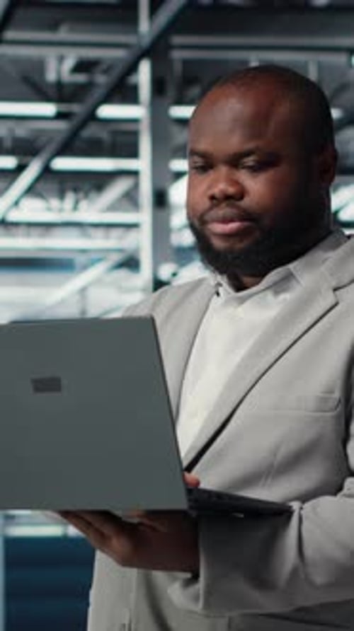 Ingénieur Vidéo vertical dans un centre de données utilisant un ordinateur portable pour mettre à jour les baies de stockage