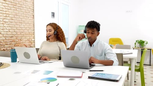 Diverse Call Center Agents Working in Office with Headsets