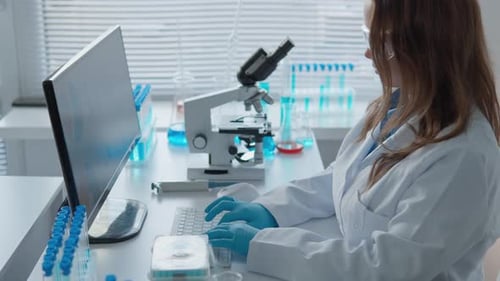 Scientist Typing at Computer in Bright Lab