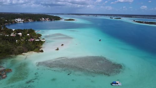 Aerial shot overseeing the white sand beaches and the town of Bacalar, Mexico. crystal blue water wi