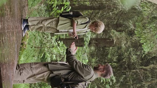Father and Son Explore Forest with Phone