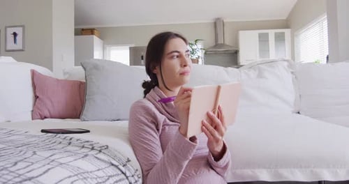 Happy caucasian woman sitting on floor and taking notes