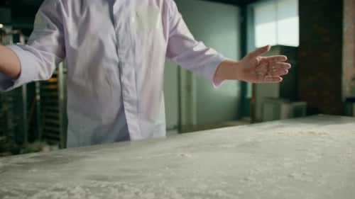 An experienced chef applies flour to his hands before making bread in a bakery prepares pastries