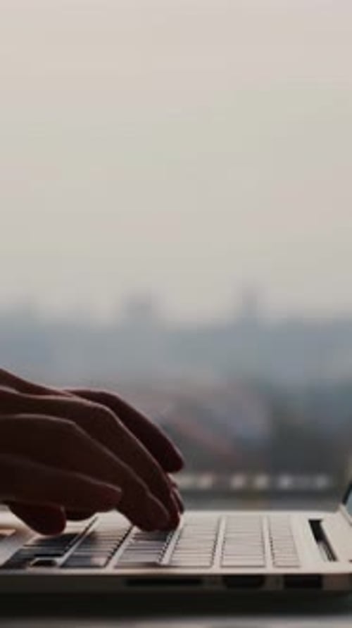 Female hands typing on laptop keyboard, close up of fingers. Vertical video