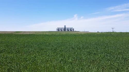 Grain Silo Nestled Among Green Fields And Blue Sky