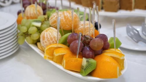 39. The buffet table is decorated with pears, oranges, grapes, kiwi.