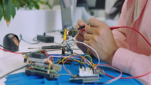 Menschenhand eines Ingenieurs misst die elektrische Spannung der Hauptplatine mit einem digitalen Multimeter