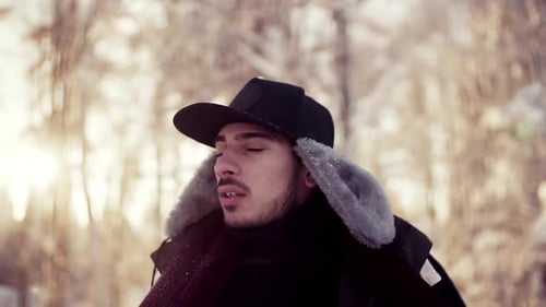 Young hispanic man enjoys winter weather standing in a snowy forest outdoors