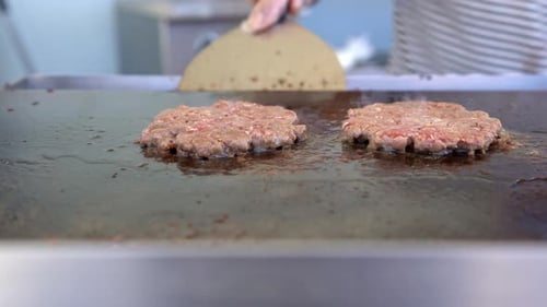 three pieces of Beef burger is cooking on the grill