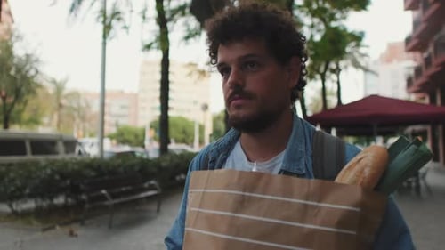 Joven feliz caminando por la calle con una bolsa de comida