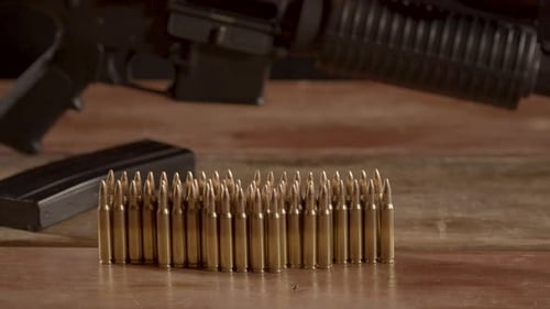 Dolly of .223 ammunition on a wooden surface with an unloaded AR-15 in the background