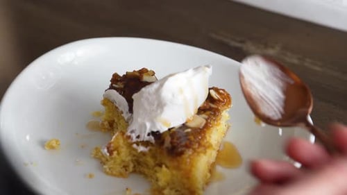 Mano femenina mientras come pastel de plátano dulce cubierto con crema batida. - Toma de ángulo alto