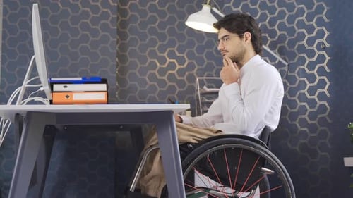 Disabled businessman working in office in wheelchair.