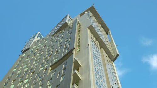 High-rise building with geometric design against blue sky.