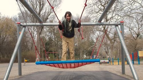 Teen Swinging on Rope Swing on Yard