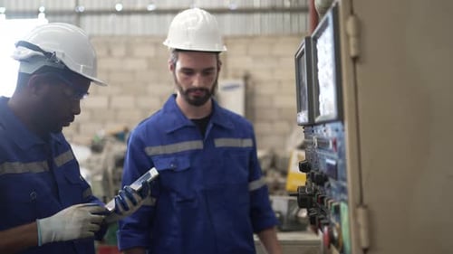Los obreros trabajan en un taller de máquinas con una máquina de torno CNC.