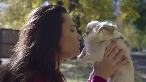 A Woman Plays with a Dog in the Autumn Park