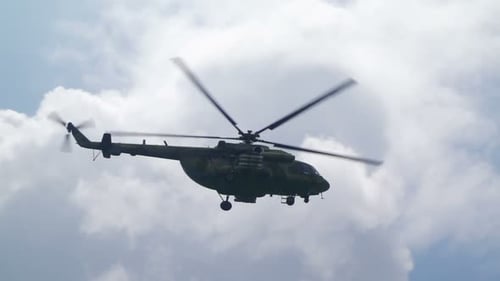 Military Helicopter flying amongst fluffy white clouds in sky
