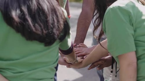 Volunteers Joining Hands in Huddle in Parking Lot 2024 Years