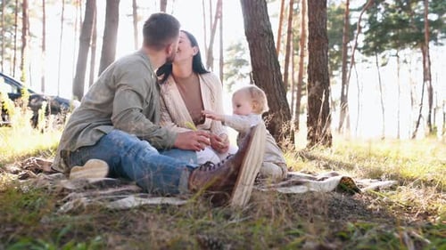 Feeding boy with child food. Family of father, mother and little son is outdoors in the forest