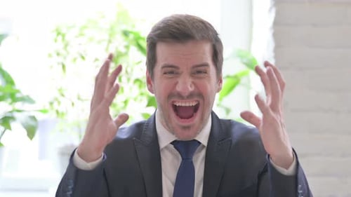 Angry Young Businessman Screaming in Frustration in Office
