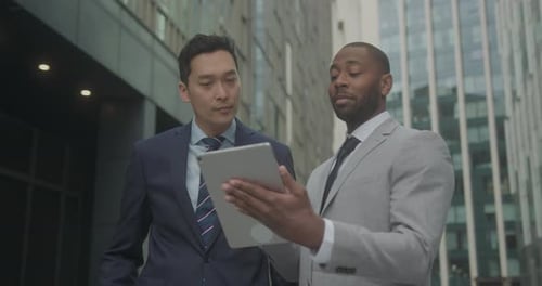 Business Men Meeting Outdoors using Digital tablet Technology on Street