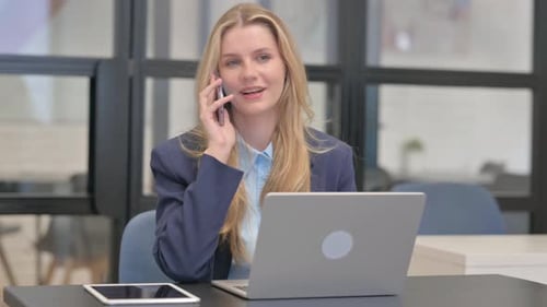 Blonde Woman Talking on Cell Phone at Desk