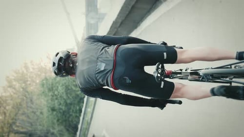 Sportive man in black helmet and cycling apparel riding bicycle. Vertical video