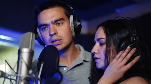 Male and female duet singing a song wearing headphones.